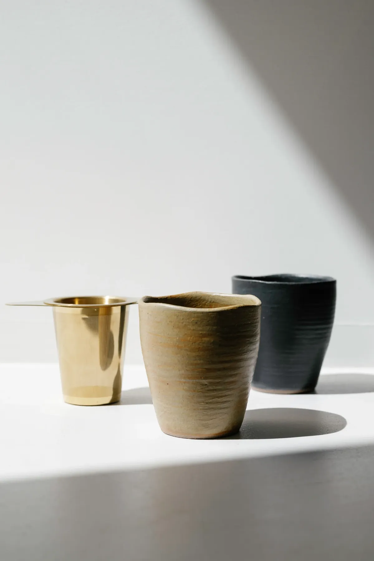 Handmade TeaGood tea cups and strainer in soft light